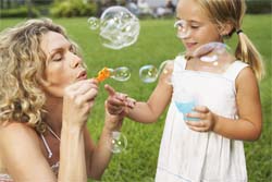 Маленькая девочка и мама пускают мыльные пузыри